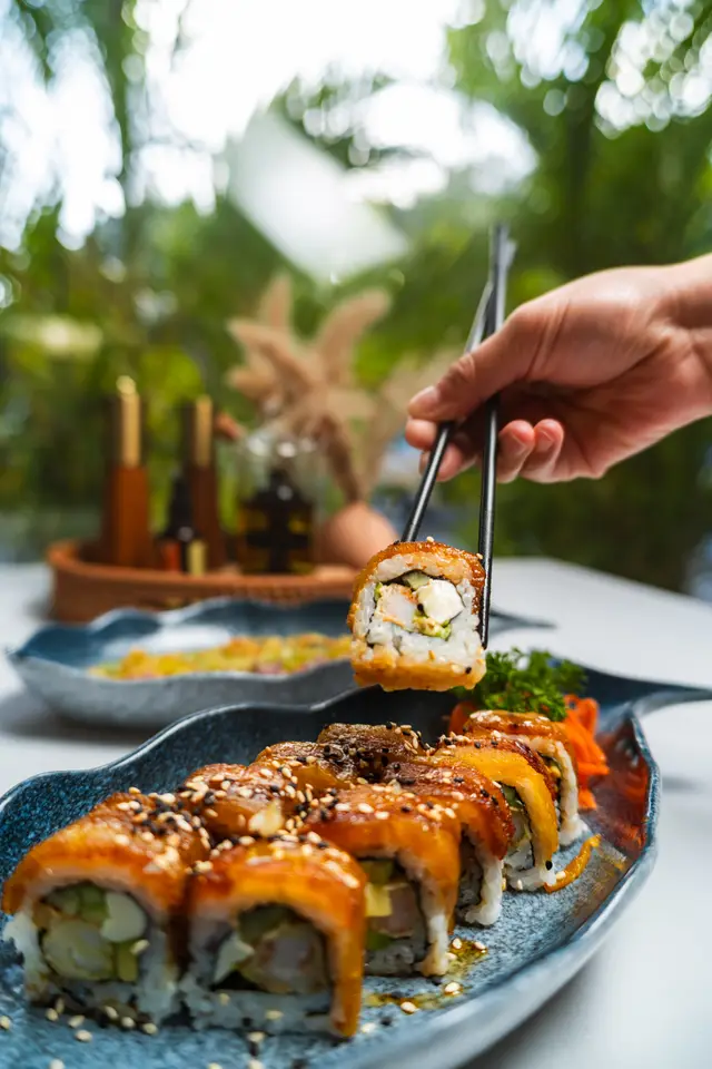 Plátano con Queso roll lifted with chopsticks