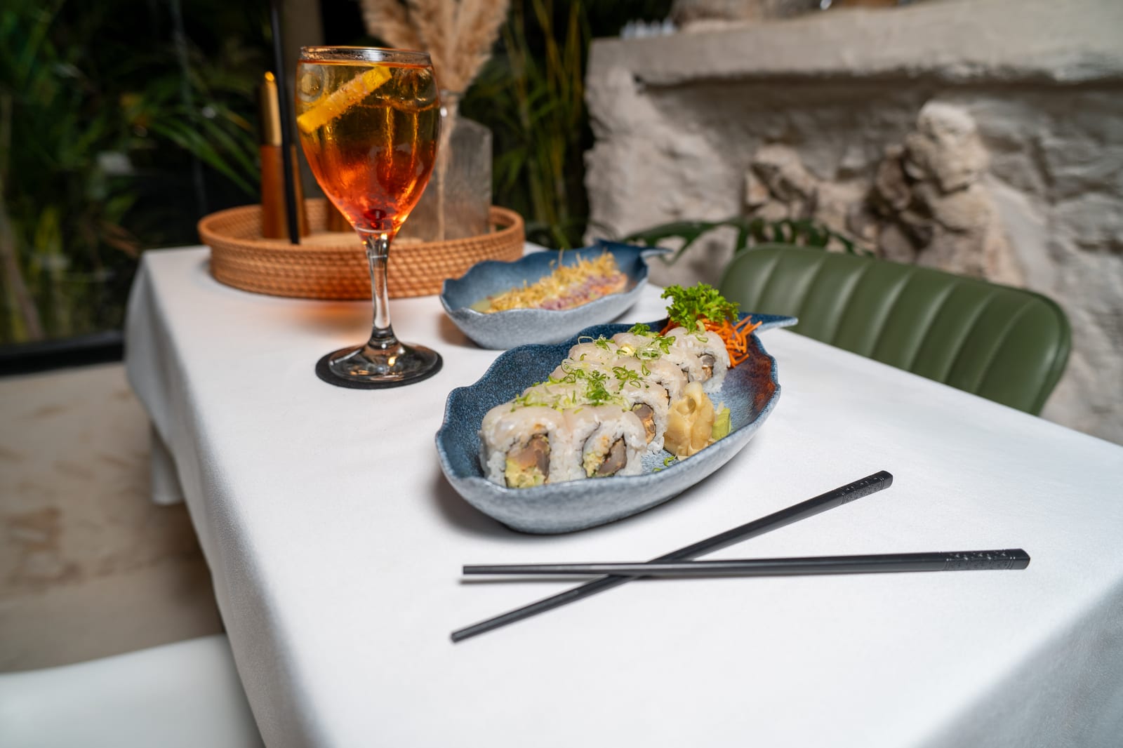 Signature sushi roll topped with white fish next to an Aperol spritz on MERO 18's night terrace