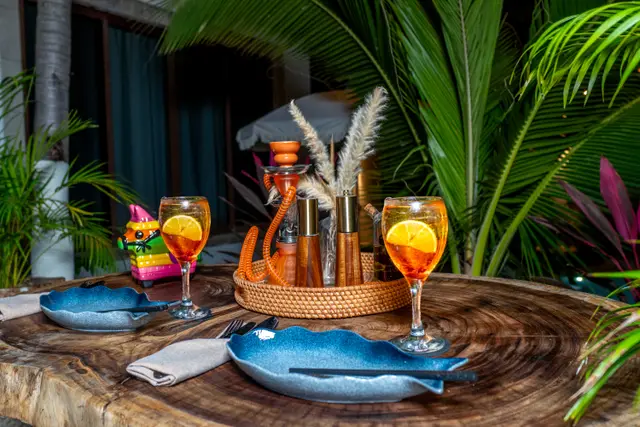 Nighttime table for two with spritz cocktails and blue plates on MERO 18's jungle patio