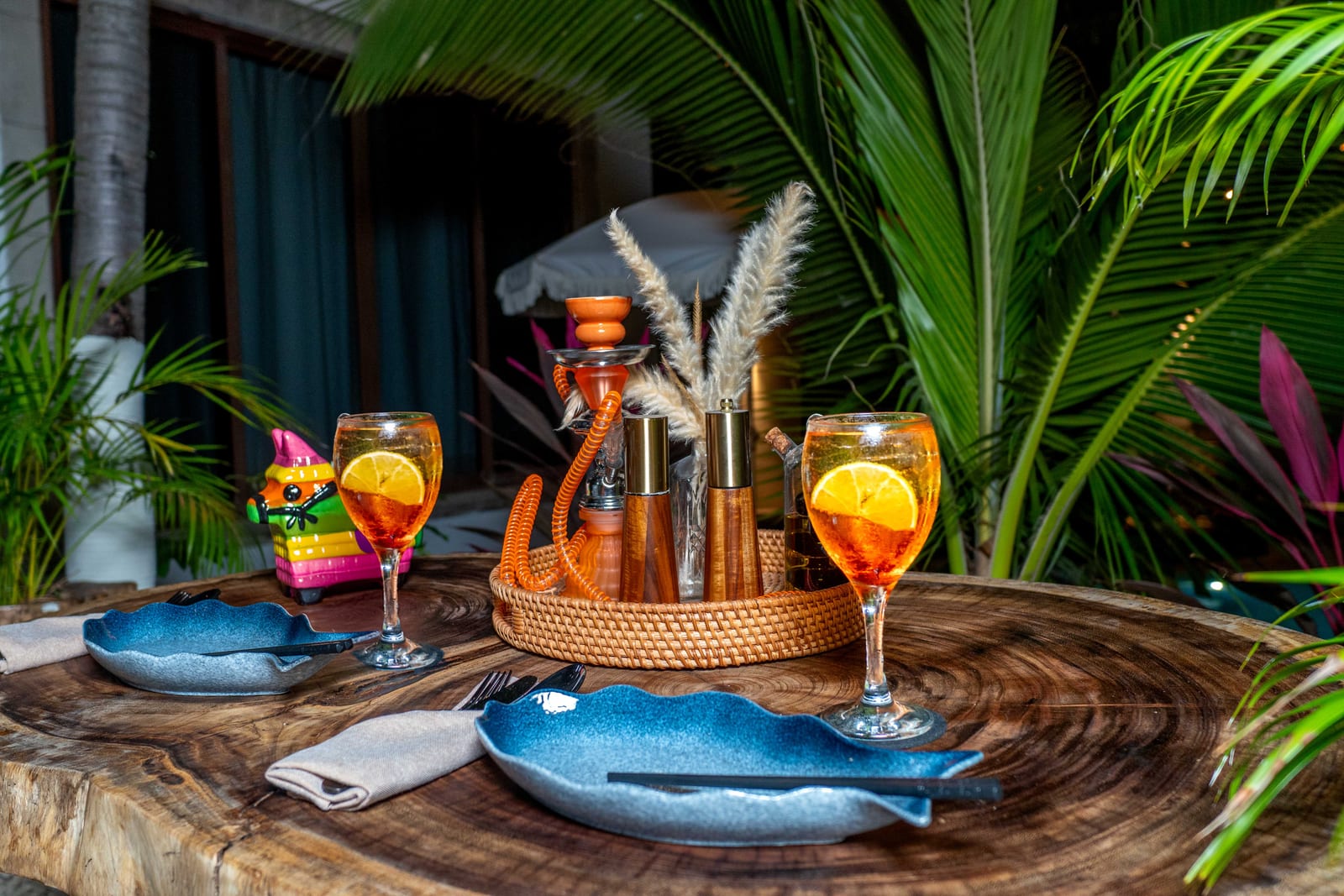 Candlelit table for two with cocktails and blue plates on MERO 18's jungle patio at night