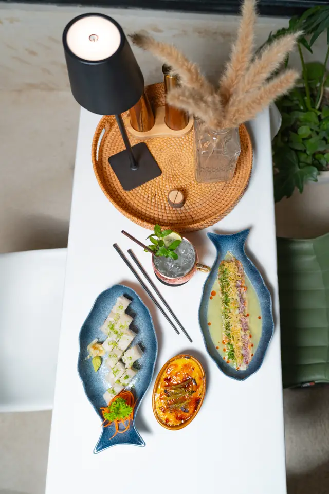 Table from above with sushi, ceviche, dessert and a cocktail