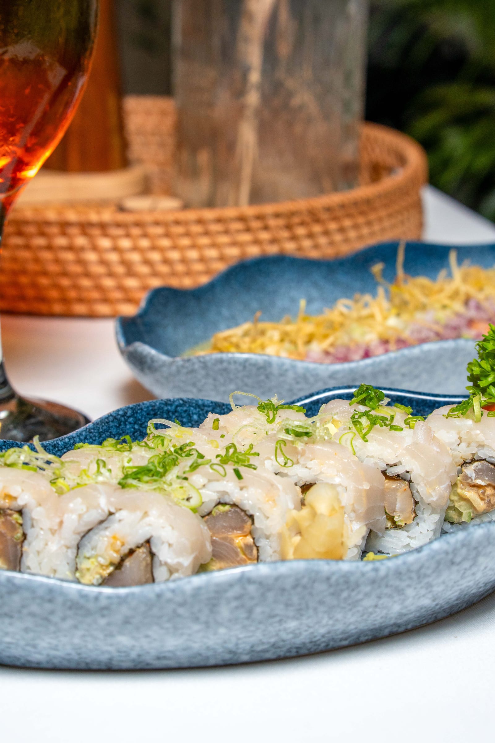 Ceviche con crujiente de camote y rollo de sushi de pescado blanco en platos azules de la barra fría de MERO 18