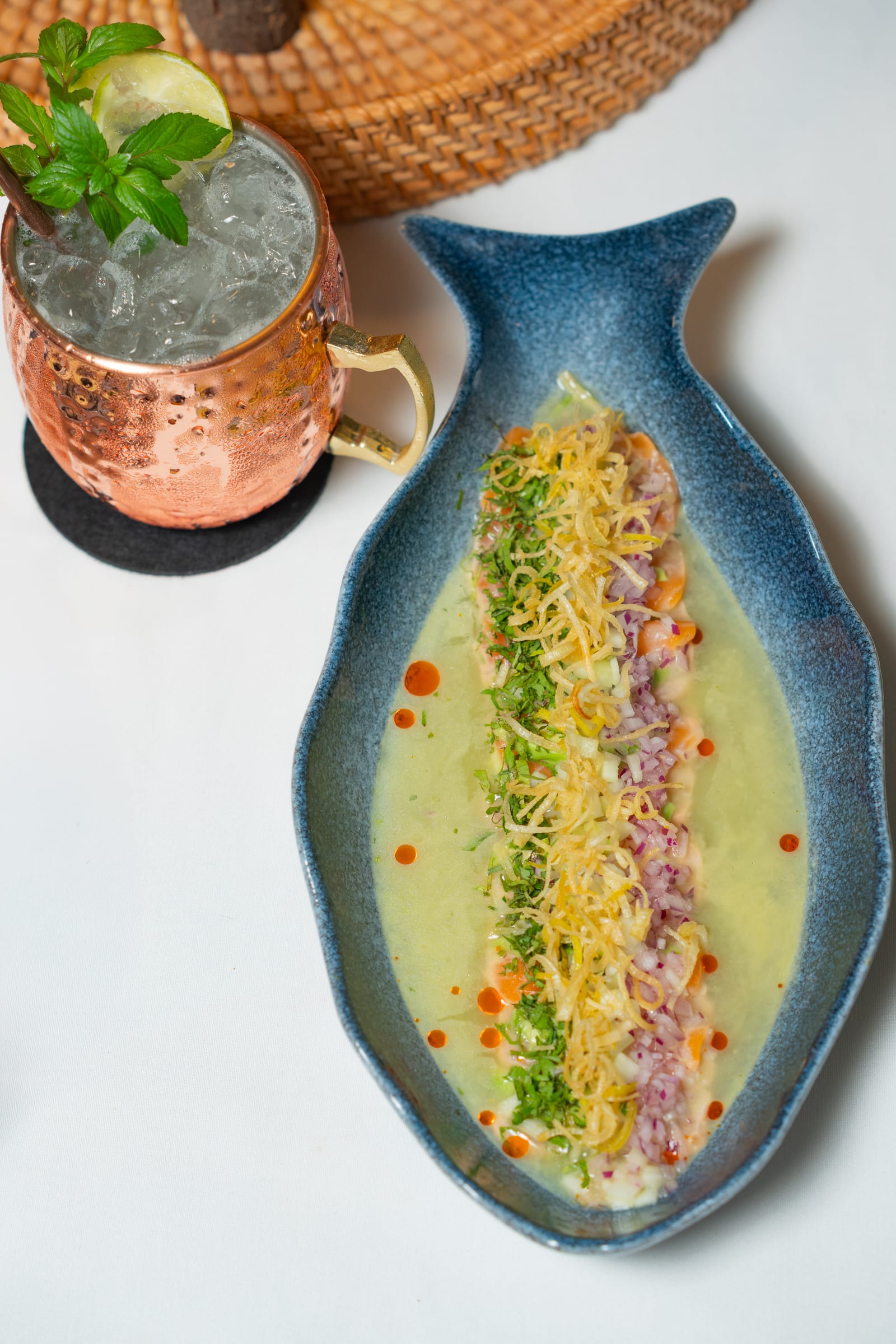 Salmon tiradito in tiger's milk on a blue fish-shaped plate