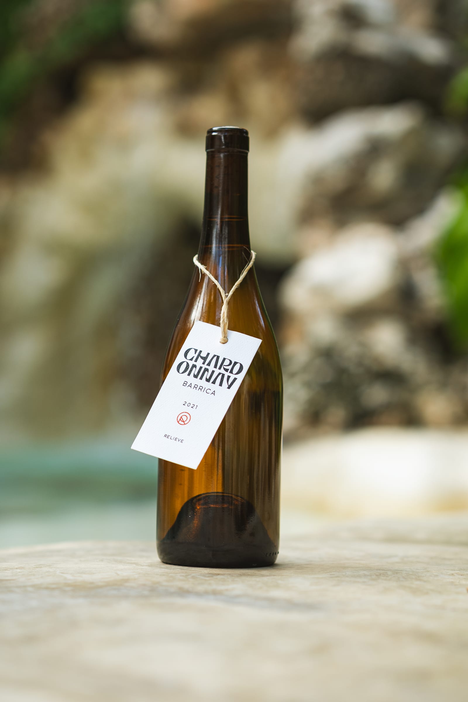 A bottle of Mexican white wine, Relieve Barrel-aged Chardonnay from Valle de Guadalupe, beside the garden waterfall at MERO 18 in Cancún, ready to pair with seafood