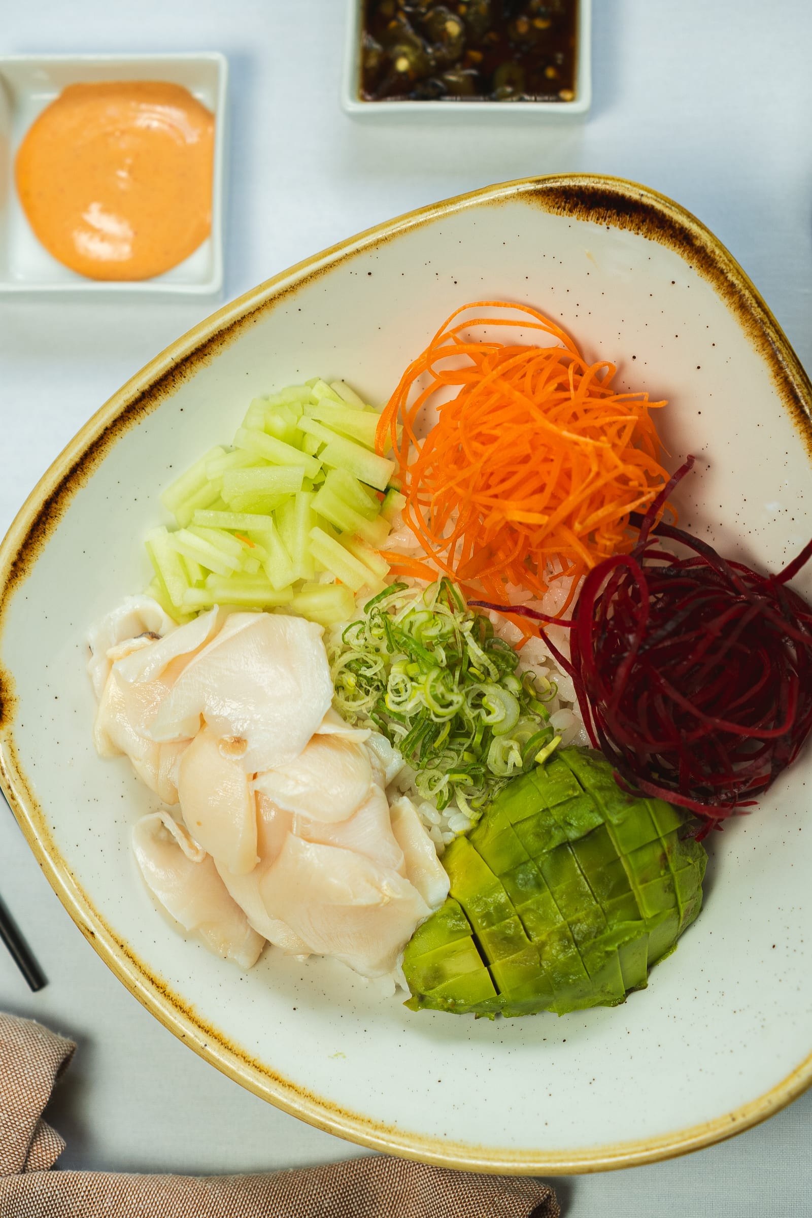 Bowl of fresh white fish sashimi slices with avocado and vegetables