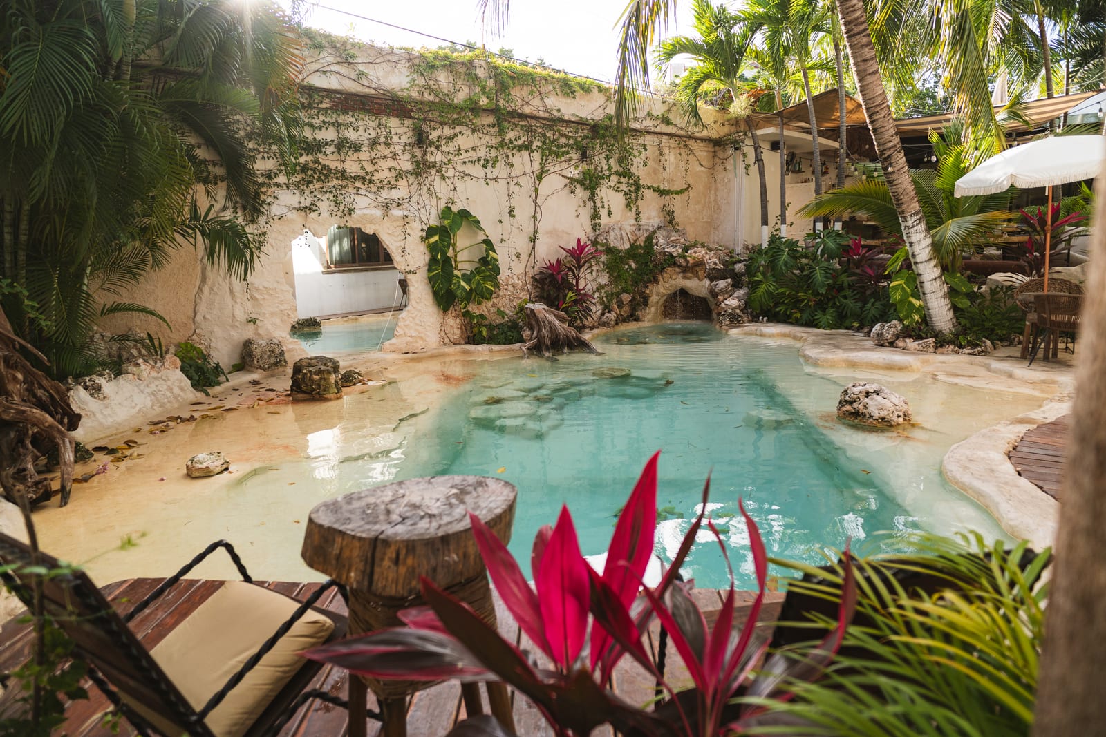 Lagoon-style pool courtyard with turquoise water, waterfall grotto and palm trees at MERO 18, downtown Cancun