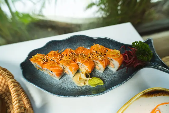 Salmon roll with crispy leek and sesame on a fish-shaped plate