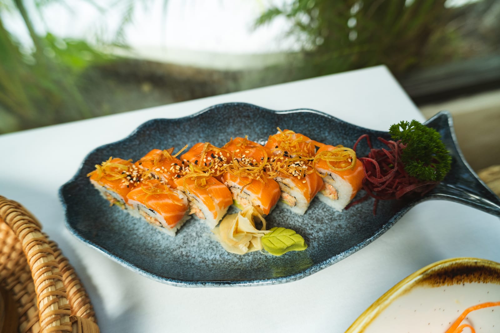 Rollo de salmón de MERO 18 cubierto de salmón fresco, crujiente de poro y ajonjolí en plato con forma de pez