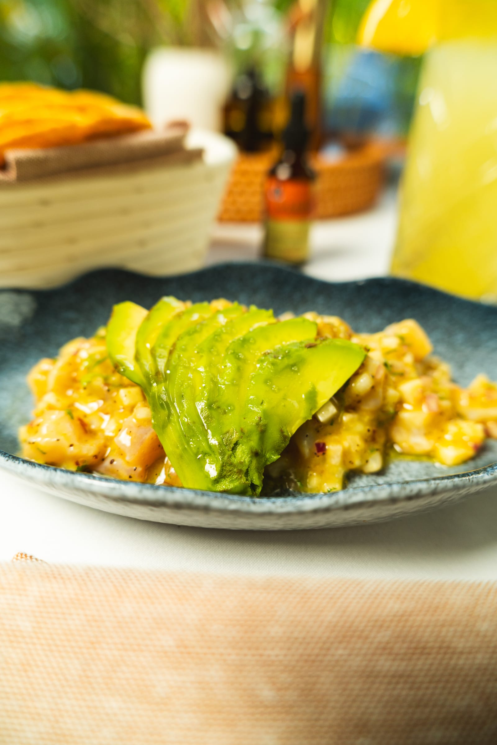 Aguachile with a fan of avocado in yellow dressing on a blue fish-shaped plate