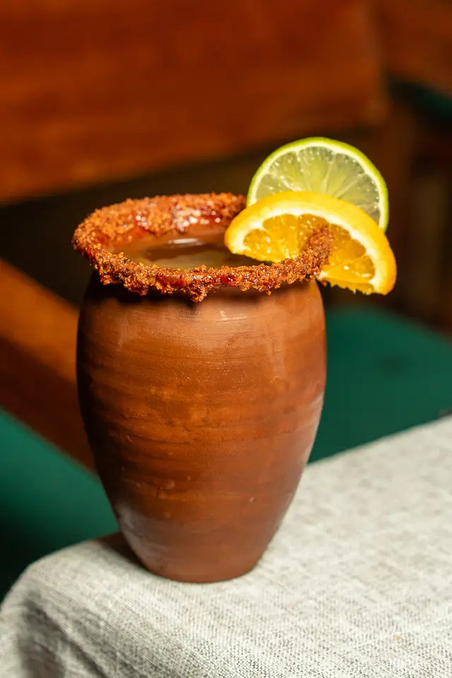 Mezcal cocktail in a clay cup with a tajín rim