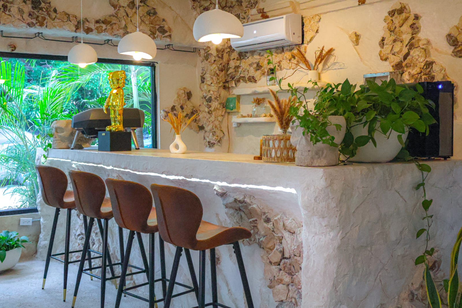 Barra interior de MERO 18 con cubierta de piedra clara, bancos de piel, plantas y lámparas colgantes
