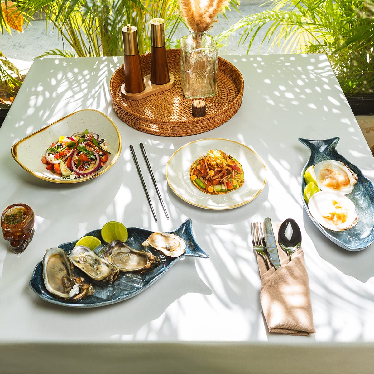 Mesa montada con ostiones frescos sobre hielo, tostada de atún y ensalada en la barra fría de MERO 18, Centro de Cancún